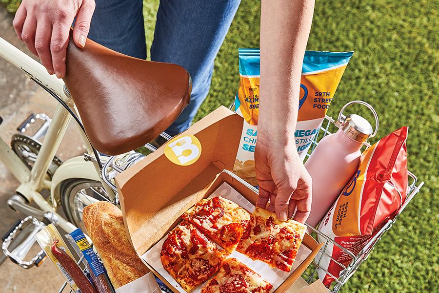 Woman with pizza and snacks on a bike.